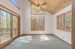 Experience breathtaking natural beauty from this stunning room, featuring expansive windows and a sliding glass door that open to a serene forest view.