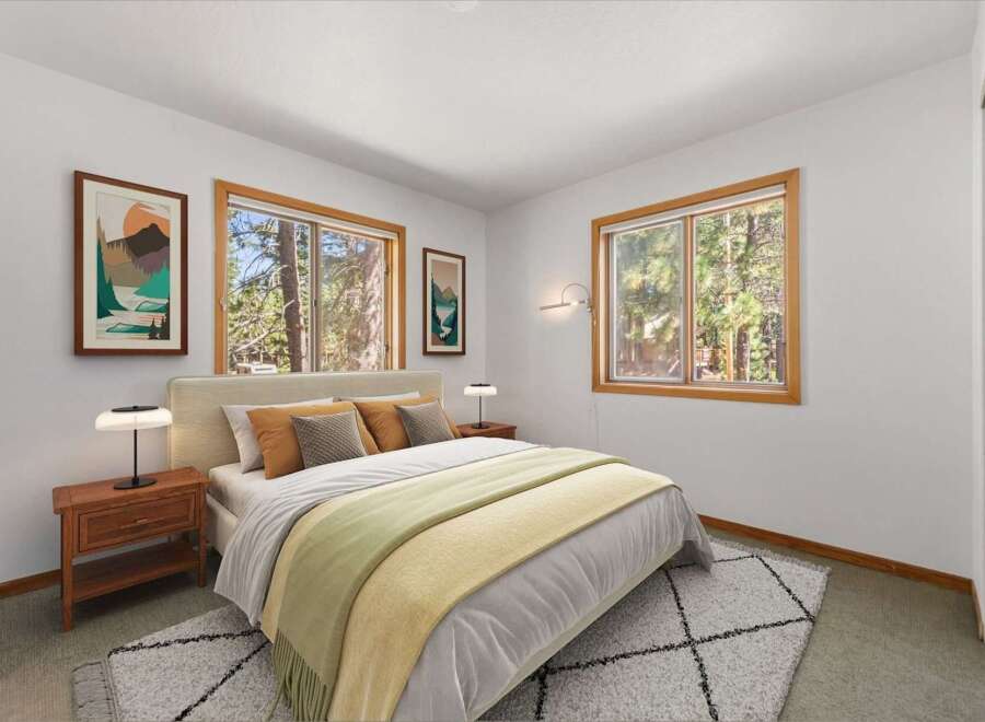 Experience serene living in this charming bedroom, featuring large windows that offer picturesque views of the surrounding forest.