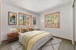 Experience serene living in this charming bedroom, featuring large windows that offer picturesque views of the surrounding forest.