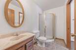 This bathroom features a vanity with a marble countertop and a wooden cabinet base, complemented by an oval wooden-framed mirror.