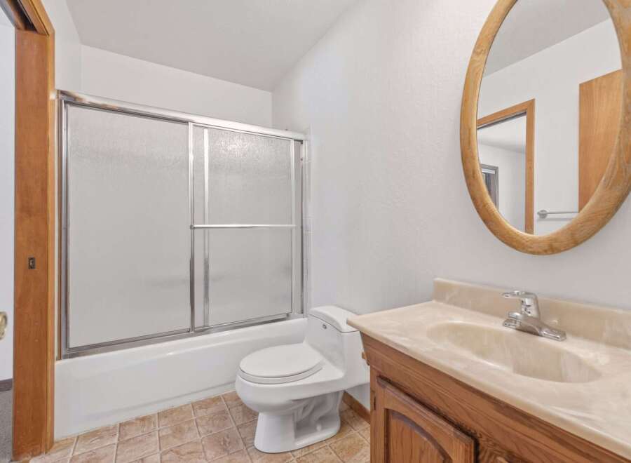 This bathroom features a clean and functional design with a white bathtub and shower combination, complemented by a modern toilet.