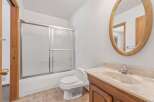 This bathroom features a clean and functional design with a white bathtub and shower combination, complemented by a modern toilet.