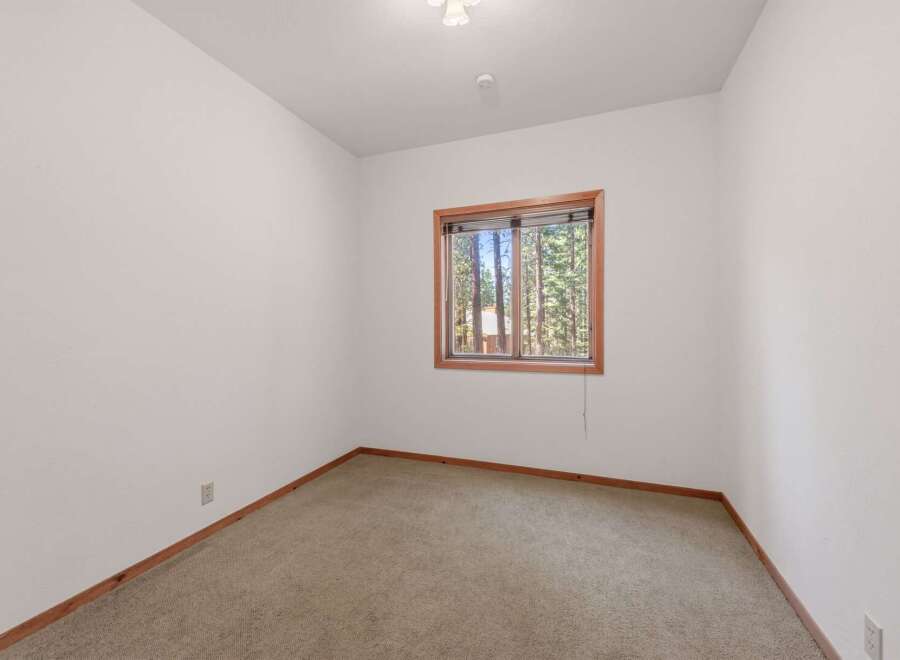 This cozy room features a large window offering picturesque views of the surrounding forest.