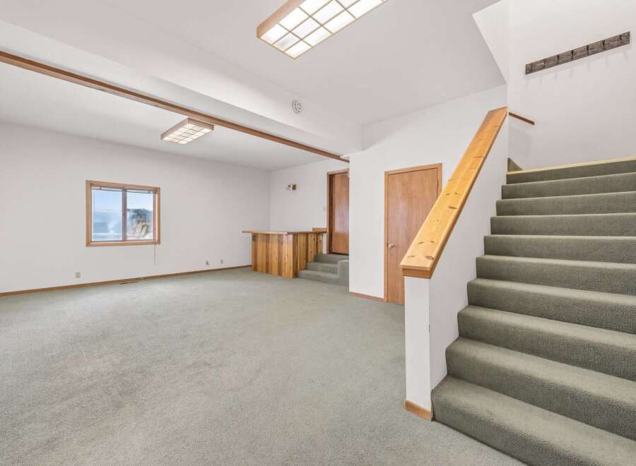 This spacious living area features a large, open-plan layout with plush carpeting and recessed lighting, creating a warm and inviting atmosphere.