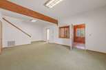 Step into this spacious living area featuring a charming wooden beam accent and a cozy, carpeted floor.