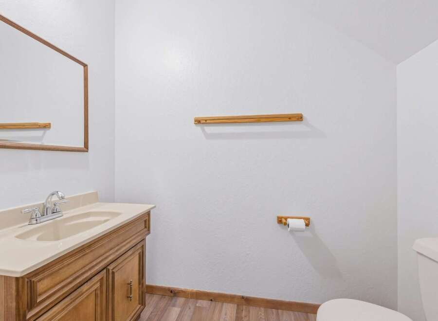 This bathroom features a wooden vanity with a beige countertop and sink, complemented by a large mirror.
