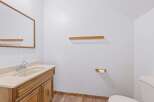This bathroom features a wooden vanity with a beige countertop and sink, complemented by a large mirror.