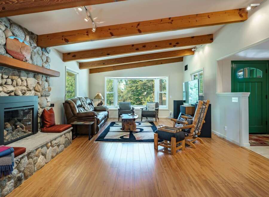 Experience rustic charm in this inviting living room, featuring a magnificent stone fireplace and exposed wooden beams that add warmth and character.