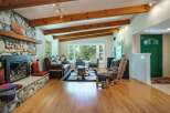 Experience rustic charm in this inviting living room, featuring a magnificent stone fireplace and exposed wooden beams that add warmth and character.