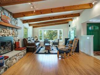 Experience rustic charm in this inviting living room, featuring a magnificent stone fireplace and exposed wooden beams that add warmth and character.