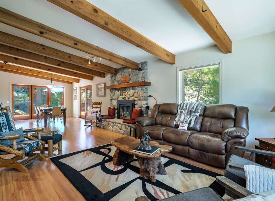 Experience rustic charm in this inviting living room, featuring a grand stone fireplace and exposed wooden beams that add warmth and character.