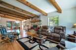 Experience rustic charm in this inviting living room, featuring a grand stone fireplace and exposed wooden beams that add warmth and character.