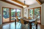 Experience seamless indoor-outdoor living in this stunning dining room, featuring expansive glass doors that open onto a private deck surrounded by lush trees.