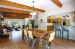 Experience rustic charm and modern comfort in this spacious open-concept living area, featuring exposed wooden beams and a cozy stone fireplace.