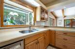 This spacious kitchen boasts a large sink area with a stunning view of the surrounding forest through a wide window.