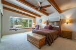 Experience rustic charm in this inviting bedroom featuring exposed wooden beams and a spacious bay window with a built-in seating area, perfect for enjoying the scenic views.