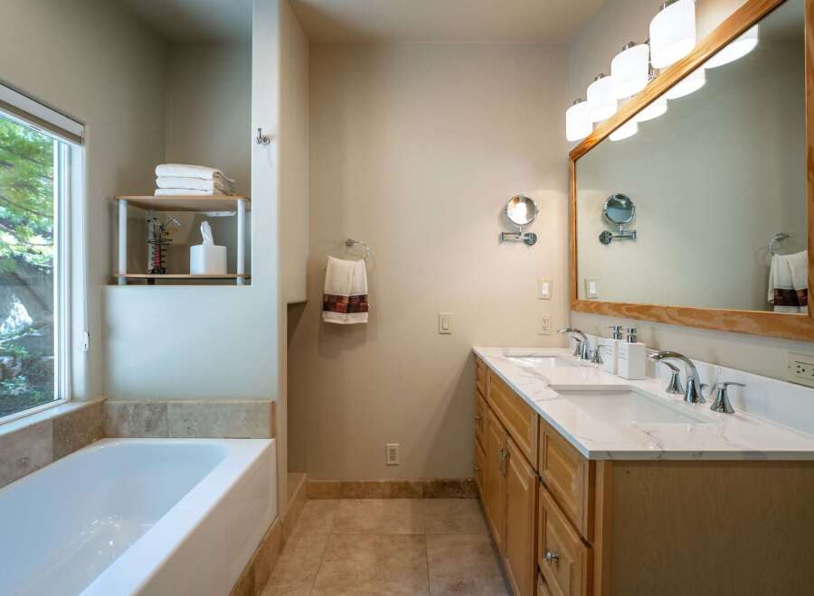 This spacious bathroom features a large soaking tub with a scenic window view, perfect for relaxation.
