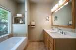 This spacious bathroom features a large soaking tub with a scenic window view, perfect for relaxation.