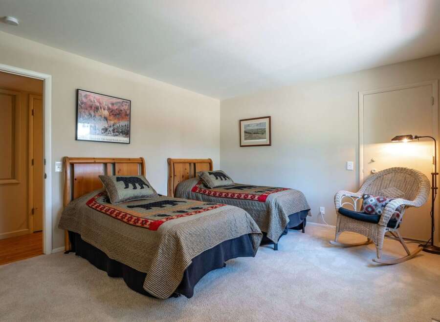 This charming bedroom features two twin beds with cozy bear-themed bedding, perfect for a rustic retreat.