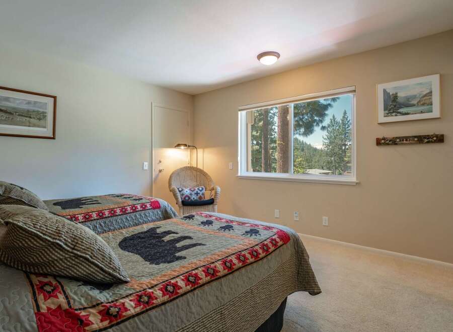 Experience cozy comfort in this charming bedroom featuring two inviting beds adorned with unique bear-themed quilts.