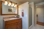 This bathroom features a spacious vanity with a granite countertop and a wooden cabinet, complemented by a large mirror with an ornate light fixture.