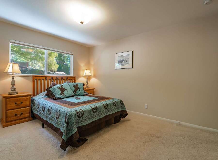 This charming bedroom features a comfortable queen-size bed adorned with rustic western-themed bedding, including pillows with horse motifs.