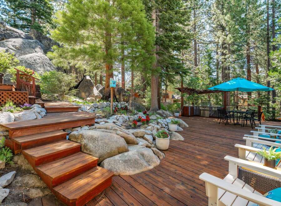 Experience outdoor living at its finest on this expansive wooden deck, perfect for entertaining or relaxing amidst a serene, wooded setting.