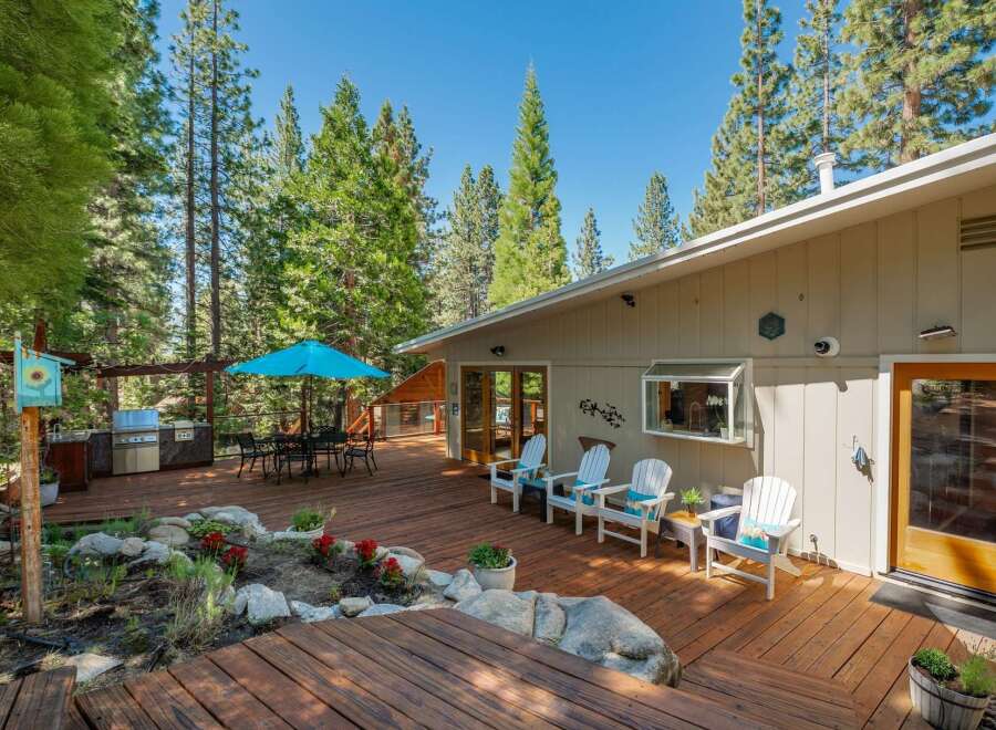 Enjoy outdoor living at its finest on this expansive wooden deck, perfect for entertaining or relaxing amidst a serene forest setting.