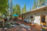 Enjoy outdoor living at its finest on this expansive wooden deck, perfect for entertaining or relaxing amidst a serene forest setting.
