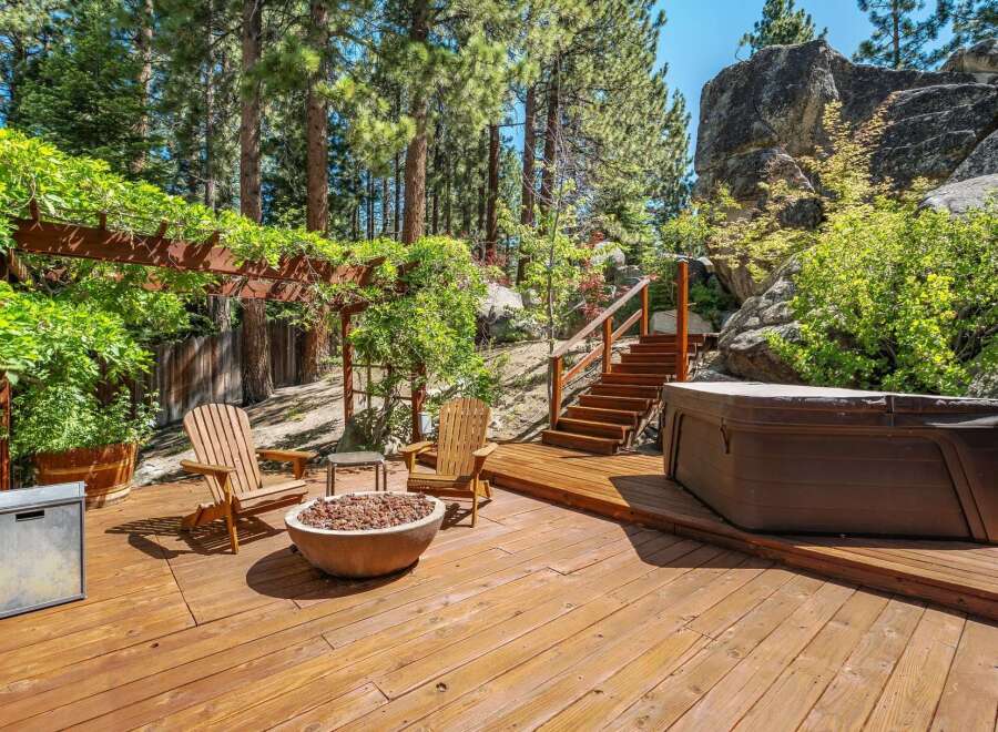 Enjoy outdoor living at its finest on this expansive wooden deck, complete with a cozy fire pit and comfortable Adirondack chairs.