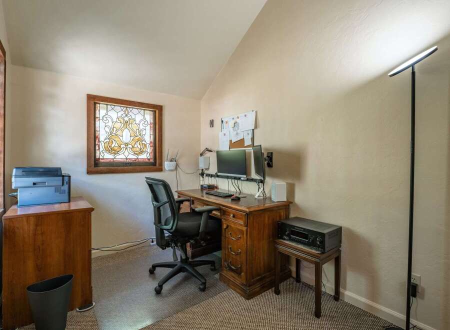 This home office features a charming stained-glass window that adds a unique artistic touch to the space.