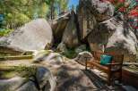 Discover a unique outdoor oasis featuring a charming wooden bench adorned with a decorative pillow, nestled amongst majestic boulders.