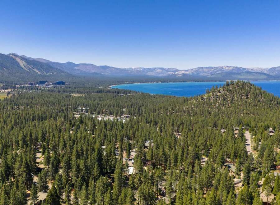 Experience the ultimate mountain lifestyle with this stunning aerial view of a property nestled amidst a dense pine forest.