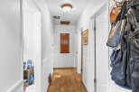 Step into this charming hallway featuring a warm wooden floor and beadboard wainscoting, creating a cozy and inviting atmosphere.