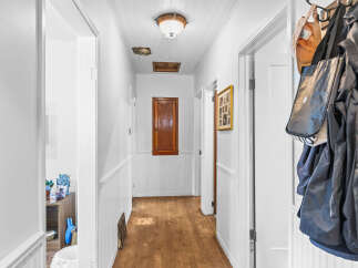 Step into this charming hallway featuring a warm wooden floor and beadboard wainscoting, creating a cozy and inviting atmosphere.