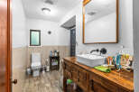 This charming bathroom features a rustic wooden vanity with a vessel sink, complemented by a dark bronze faucet.