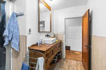 This charming bathroom features a rustic wooden vanity with a modern vessel sink, complemented by a large wooden-framed mirror.