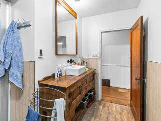 This charming bathroom features a rustic wooden vanity with a modern vessel sink, complemented by a large wooden-framed mirror.