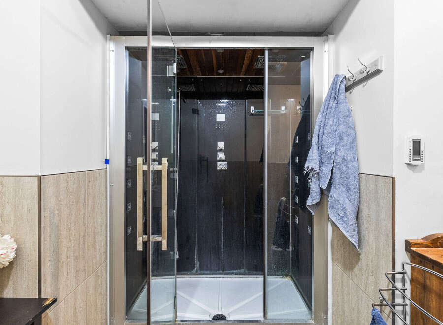 Experience ultimate relaxation in this modern bathroom featuring a sleek glass-enclosed shower with a black interior and multiple jets.