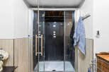 Experience ultimate relaxation in this modern bathroom featuring a sleek glass-enclosed shower with a black interior and multiple jets.