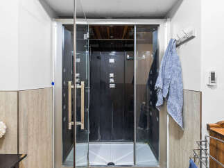 Experience ultimate relaxation in this modern bathroom featuring a sleek glass-enclosed shower with a black interior and multiple jets.