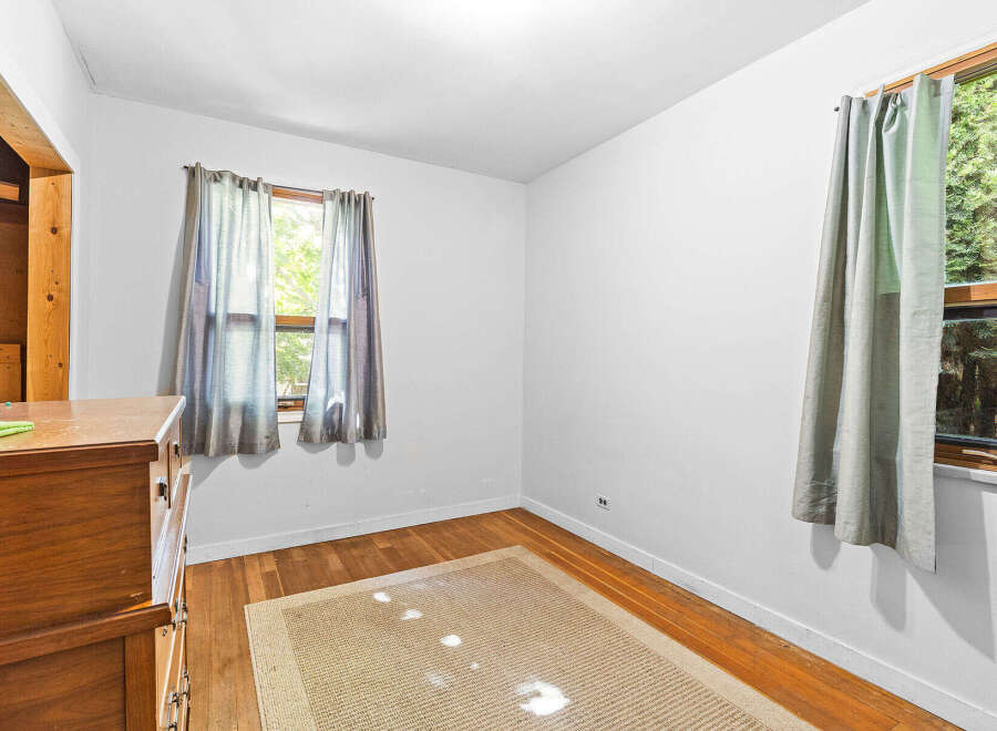 This charming room features a warm wooden dresser and a neutral-toned rug, creating a cozy atmosphere.