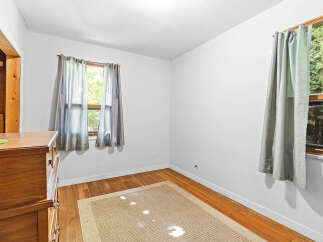 This charming room features a warm wooden dresser and a neutral-toned rug, creating a cozy atmosphere.