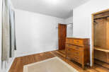 Discover this charming bedroom featuring a classic wooden dresser and a convenient closet with shelving.