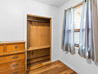 Discover ample storage in this charming bedroom, featuring a spacious closet with a built-in shelf and hanging rod.