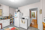 Discover this charming kitchen featuring white appliances, including a refrigerator and a stove with a stovetop pan.
