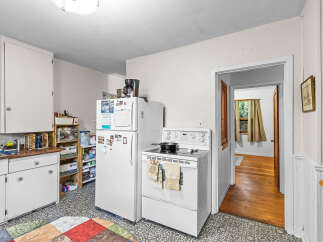 Discover this charming kitchen featuring white appliances, including a refrigerator and a stove with a stovetop pan.