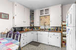 Discover a charming kitchen featuring ample white cabinetry for storage and a cozy dining nook with a colorful quilt-patterned tablecloth.