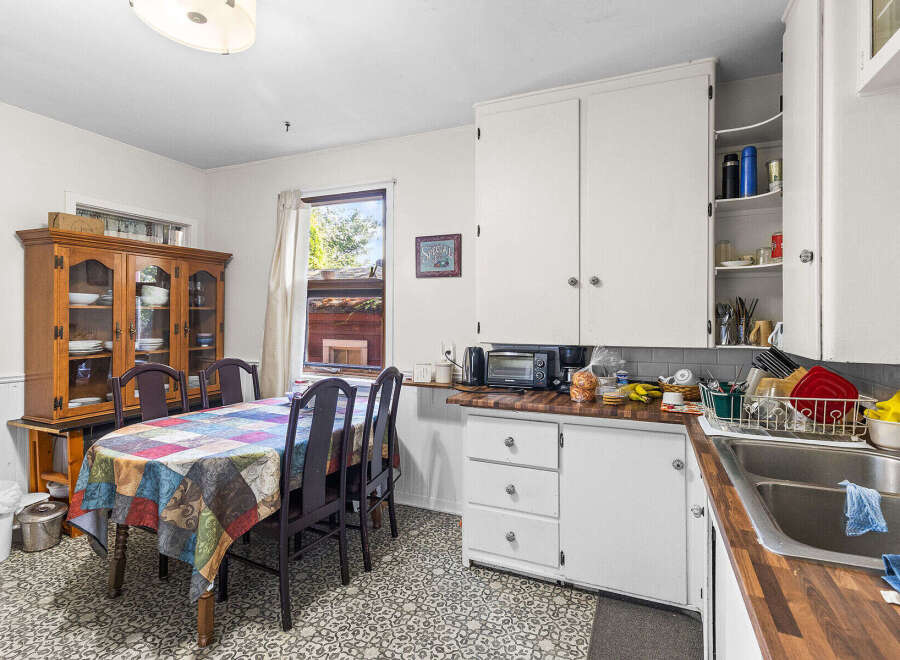 This charming kitchen features a spacious dining area with a colorful, patterned tablecloth and a traditional wooden hutch perfect for displaying dishware.