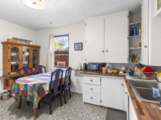 This charming kitchen features a spacious dining area with a colorful, patterned tablecloth and a traditional wooden hutch perfect for displaying dishware.
